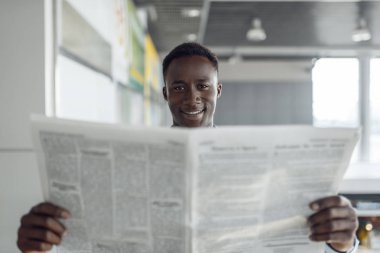 Ofis koridorunda gazetesi olan Afrikalı bir işadamı. Başarılı iş adamı alıntıları okur