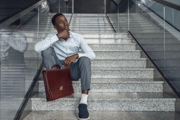 African businessman with briefcase sitting on stairs