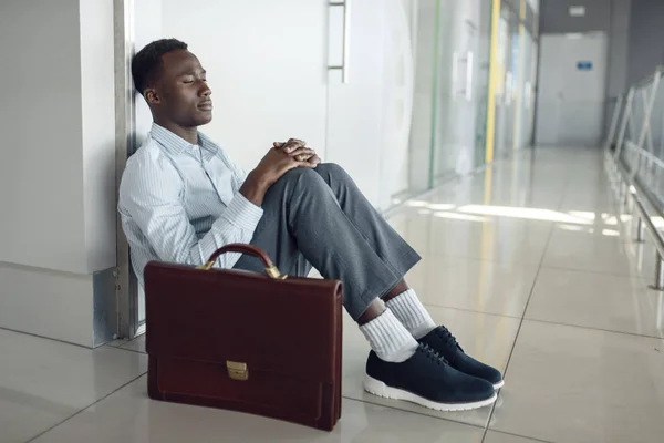 사무실 바닥에 가방을 아프리카 사업가입니다 사업가는 복도에서 휴식을 취하고 남자는 — 스톡 사진