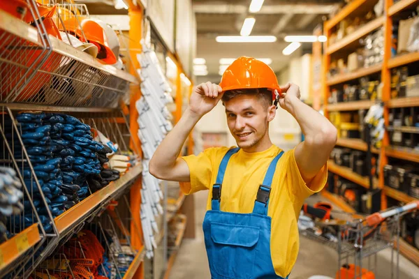 Construtor Masculino Tentando Capacete Prateleira Loja Ferragens Construtor Uniforme Olhar — Fotografia de Stock