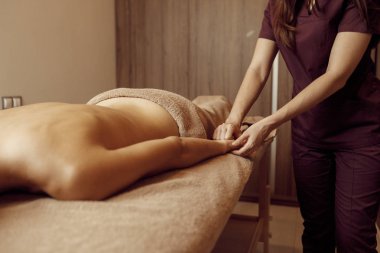 Kadın masör, havluyla sıska genç bir kadına, profesyonel masajla pohpohluyor. Masaj ve rahatlama, vücut ve cilt bakımı. Kaplıca salonundaki çekici bayan.