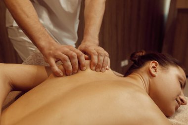 Erkek masör sıska bir kadına havluyla el masajı yapıyor, profesyonel masaj. Masaj ve rahatlama, vücut ve cilt bakımı. Kaplıca salonundaki çekici bayan.