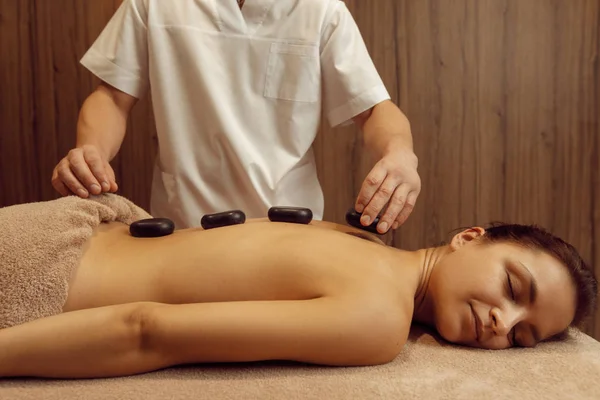 Male Masseur Puts Stones Back Slim Woman Towel Professional Massage — Stock Photo, Image