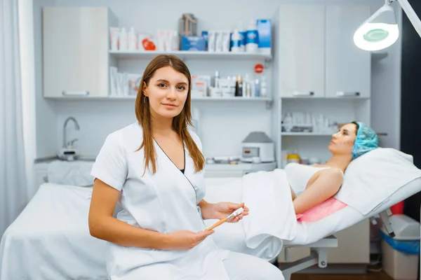 治療テーブル上の女性患者の近くの化粧品 ボックス注射の準備 美容室での若返りの手順 医師と女性 しわや老化に対する美容整形 — ストック写真