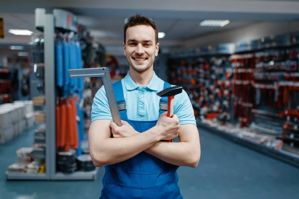 Sonriente Trabajador Masculino Uniforme Sostiene Martillo Esquina Tienda Herramientas Elección — Foto de Stock