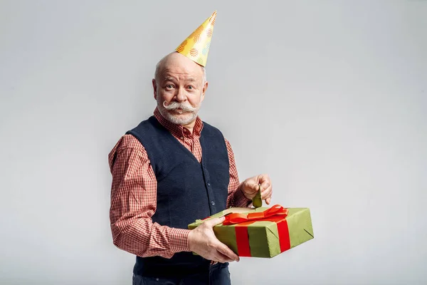Happy Elderly Man Party Cap Holds Gift Box Grey Background — Stock Photo, Image