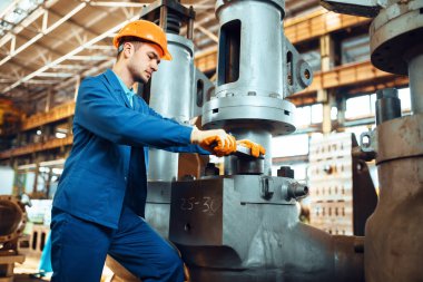Üniformalı ve kasklı mühendis fabrikada çalışıyor. Endüstriyel üretim, metal mühendisliği, güç makineleri üretimi