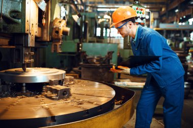 Otomatik torna tezgahında duran üniformalı ve kasklı Turner. Endüstriyel üretim, metal mühendisliği, imalat