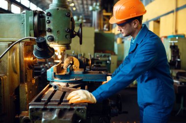 Üniformalı ve kasklı Turner torna tezgahında çalışıyor. Endüstriyel üretim, metal mühendisliği, güç makineleri üretimi