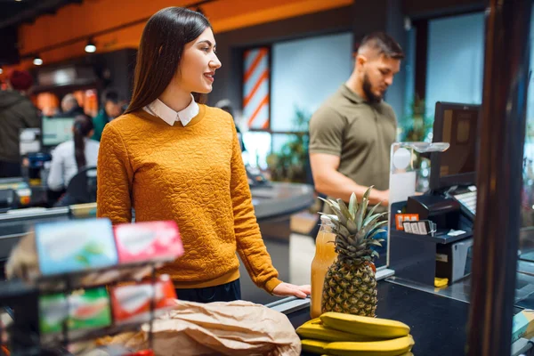 Family couple at the checkout in grocery store. Man and woman with cart buying beverages and products in market, customers paying for food and drinks in supermarket