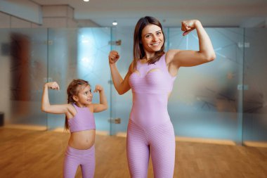 Anne ve kız spor salonundaki kasları, sağlıklı yaşam tarzını, spor salonunu gösteriyor. Anne ve küçük kız spor giyim sektöründe, çocuklu bir kadın spor kulübünde ortak antrenman yapıyor.