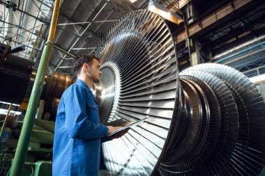 Erkek mühendis türbin iticilerini kontrol ediyor. Endüstriyel üretim, metal mühendisliği, makine imalatı