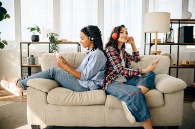 İki kadın arka arkaya müzik dinlemekten hoşlanır. Kulaklıklı güzel kız arkadaşlar odada dinlenir, ses severler kanepede dinlenir, bayan arkadaşlar birlikte vakit geçirir.