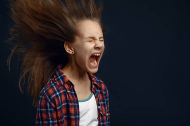 Küçük kız stüdyoda çığlık atıyor, saç efekti geliştiriyor. Çocuklar ve rüzgar, karanlık arka planda izole çocuk, çocuk duygusu