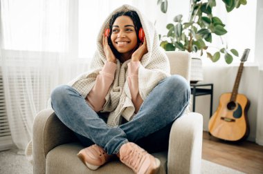 Kulaklıklı hoş bir kadın müzik dinliyor, arka planda gitar var. Kulaklıklı güzel bayan odada dinleniyor, kadın ses aşığı dinleniyor.