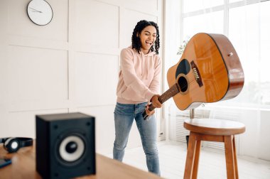 Deli kadın ses hoparlörünün yanındaki gitarı kırıyor, müzik çıldırtıyor. Güzel bayan odada dinleniyor, bayan ses aşığı dinleniyor.