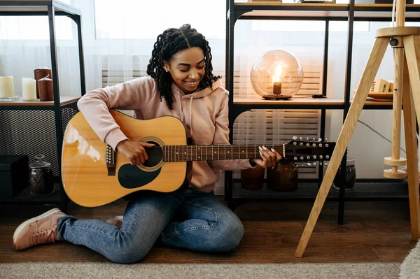 女性は床に座って 自宅でギターを演奏し クローズアップビュー 楽器を持つ美しい女性が部屋でリラックス 女性音楽愛好家休息 — ストック写真
