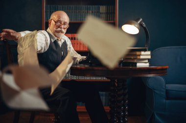 Yaşlı yazar ev ofisine kağıt çarşaf fırlatıyor. Gözlüklü yaşlı adam odada sigara ve ilham dolu edebiyat romanı yazıyor.