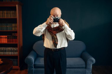 Yaşlı yazarın ofisinde retro fotoğraf makinesi var. Gözlüklü yaşlı adam odada sigara ve ilham dolu edebiyat romanı yazıyor.