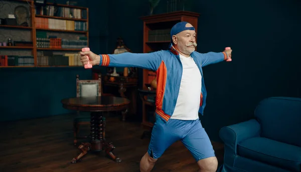 家庭でダンベルと一緒に運動する制服を着た高齢のスポーツマン フィットネストレーニング室内で成人男性 高齢者の健康的なライフスタイル — ストック写真