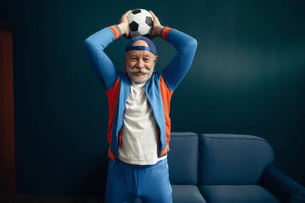 自宅でボールで制服姿の高齢スポーツマンがポーズ フィットネストレーニング室内で成人男性 高齢者の健康的なライフスタイル — ストック写真