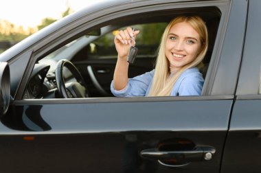 Anahtarı olan mutlu kadın arabada poz veriyor, sürücü kursunda ders veriyor. Hanımefendi araba sürmeyi öğreniyor. Sürücü ehliyeti eğitimi