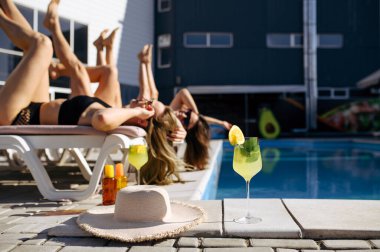 Mayo giymiş güzel kadınlar tatil köyündeki havuzda güneşleniyorlar. Güzel kızlar güneşli bir günde havuz başında dinlenirler, yaz tatillerinde çekici kız arkadaşlar.