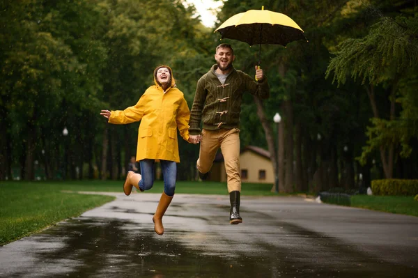 快乐的情侣在公园里跳跃 夏日雨天 男人和女人在雨伞下 浪漫的约会在人行道上 潮湿的天气在小巷里 — 图库照片