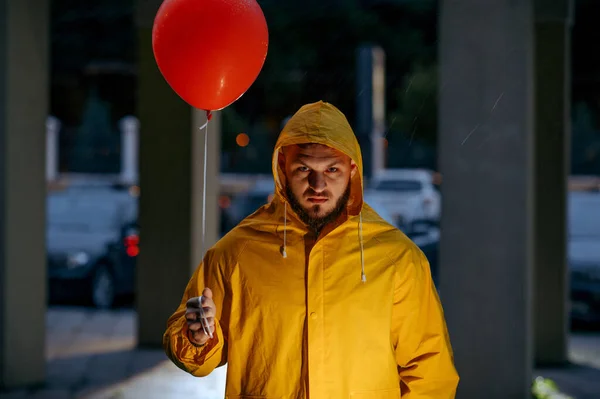 雨天带着气球在夏夜公园散步的可怕男人 奇怪的男人穿着雨衣 潮湿的天气在小巷里 — 图库照片