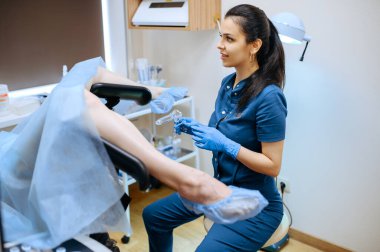 Eldivenli ve üniformalı kadın jinekolog. Klinikte jinekolojik muayene, jinekoloji teşhisi veya konsültasyon, hastanede doktor ve hasta