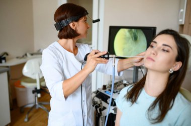 Kadın laringolog ve hasta sandalyede, otoskop. Klinikte kulak muayenesi, profesyonel teşhis, doktor. Tıbbi uzman ve hastanede bir kadın.