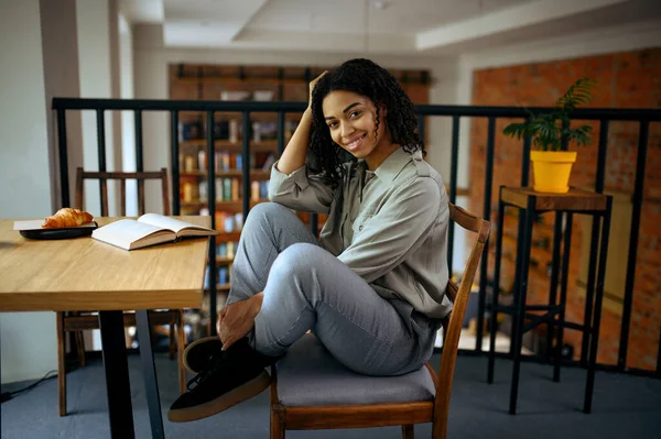 図書館のカフェのテーブルに座っている陽気な女性学生 女性は主題 教育および知識を学ぶ 女子学生食堂で勉強 — ストック写真