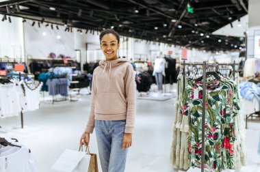 Manken gibi duran sevimli bir kadın, giyim mağazası. Moda mağazasında alışveriş yapan kadın, alışverişçi, kıyafet arayan kadın.