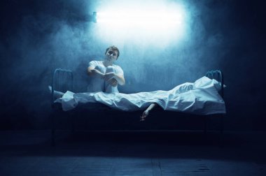 Yatakta ölü bir kadının yanında oturan psikopat adam, arka planda karanlık oda. Psikedelik kişilik her gece sorun yaşıyor, depresyon ve stres, üzüntü, psikiyatri hastanesi