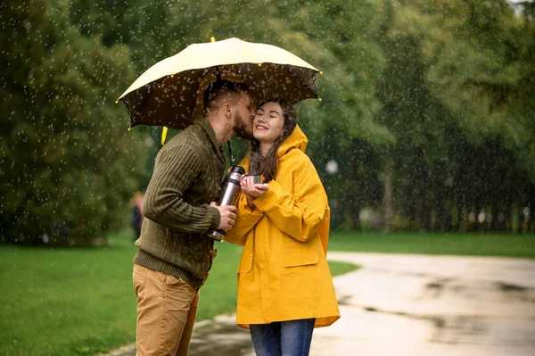 夏の雨の日 公園で熱いお茶を飲むカップルが大好きです 男と女は雨の中で傘の下で立ちます パス上のロマンチックな日付 路地で雨の日 — ストック写真