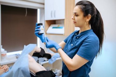 Eldivenli ve üniformalı kadın jinekolog teste bakıyor. Klinikte jinekolojik muayene, jinekoloji teşhisi veya konsültasyon, hastanede doktor ve hasta