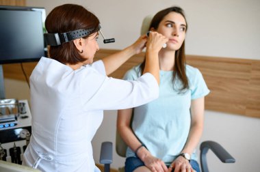 Kadın doktor ve hasta muayenede. Klinikte kulak muayenesi, profesyonel teşhis. Laringologların ofisinde tıp uzmanı ve kadın.