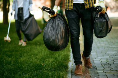 Genç adam parkta plastik çöp torbalarını tutuyor, gönüllü olarak. Erkek kişi ormanı temizler, ekolojik restorasyon, ekolojik yaşam tarzı, çöp toplama ve geri dönüşüm, ekoloji bakımı