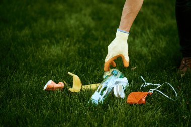 Genç adam parkta çöp topluyor, gönüllü olarak. Erkek kişi ormanı temizler, ekolojik restorasyon, ekolojik yaşam tarzı, çöp toplama ve geri dönüşüm, ekoloji bakımı, çevre temizliği