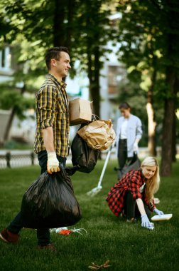 Genç adam parkta plastik çöp torbalarını tutuyor, gönüllü olarak. Erkek kişi ormanı temizler, ekolojik restorasyon, ekolojik yaşam tarzı, çöp toplama ve geri dönüşüm yapar
