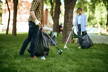 İki adam parktaki poşetlerde gönüllü olarak plastik çöp topluyor. Erkek kişi ormanı temizler, ekolojik restorasyon, ekolojik yaşam tarzı, çöp toplama ve geri dönüşüm, ekoloji bakımı, çevre temizliği