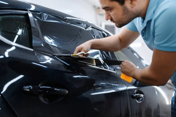 Mężczyzna Pracownik Posiada Arkusz Folii Instalację Barwienia Samochodu Serwis Strojenia — Zdjęcie stockowe