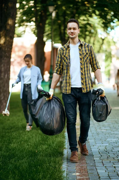 Joven Sostiene Bolsas Basura Plástico Parque Voluntariado Hombre Limpia Bosque —  Fotos de Stock