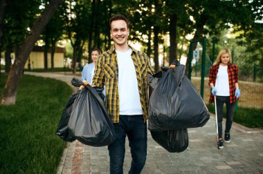 Gönüllüler, gönüllü olarak parktaki tüm plastik çöp torbalarını tutuyorlar. Erkek kişi ormanı temizler, ekolojik restorasyon, ekolojik yaşam tarzı, çöp toplama ve geri dönüşüm, ekoloji bakımı, çevre temizliği