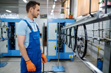 Montaj hattındaki işçiler fabrikada bisiklet tekerlekleri yapıyor. Atölyede bisiklet jantları ve jantlar üretiliyor, bisiklet parçaları kurulumu