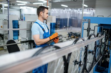 Makine aletindeki işçiler fabrikada bisiklet jantları yapıyorlar. Atölyede bisiklet tekerlekleri montajı, bisiklet parçaları kurulumu