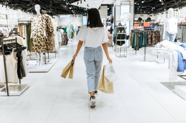 Karton çantalı kadın, giyim mağazası. Moda mağazasından alışveriş yapan bir kadın, alışverişkolik, alışverişçi.