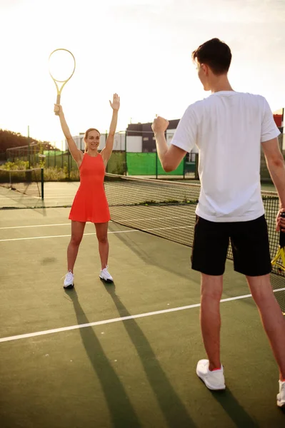 Man and woman play tennis, training on outdoor court. Active healthy lifestyle, people play sport game, fitness workout with racquets