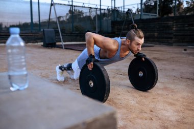 Atletik adam ağırlık kaldırma egzersizi yapıyor, sokak antrenmanı, yaya geçidi. Spor sahasında spor eğitimi, erkek kişi kas pompalıyor, aktif şehir yaşam tarzı