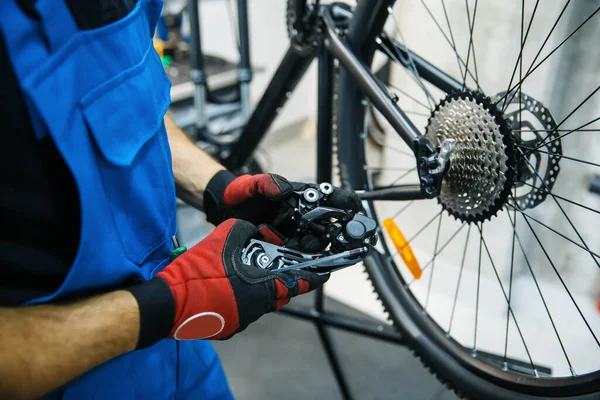 自転車修理工場 男はスピードスイッチを設定します サイクル プロの自転車修理サービスで均一な修正問題の機械 — ストック写真